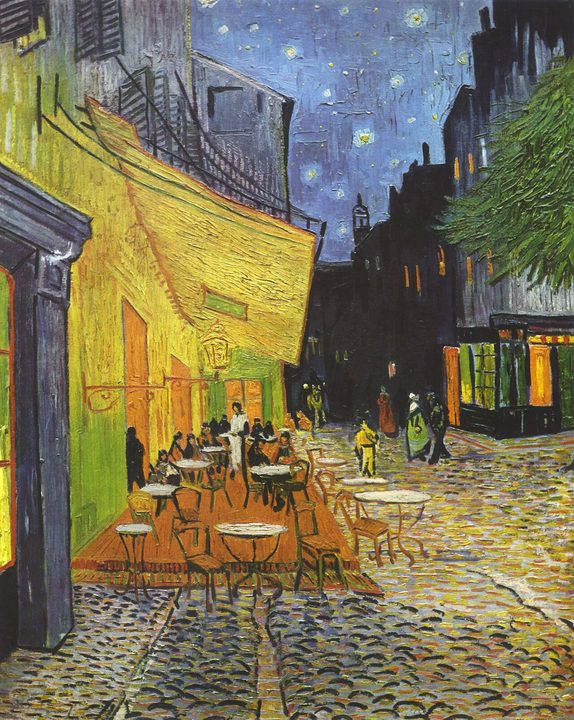 A café terrace lit yellow by its lamp, on a cobbled street under a starry blue sky